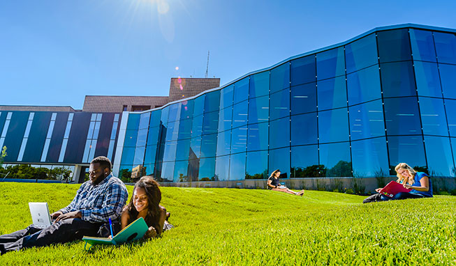 Students studying outside on the rolling lawn outside the Gannon glass